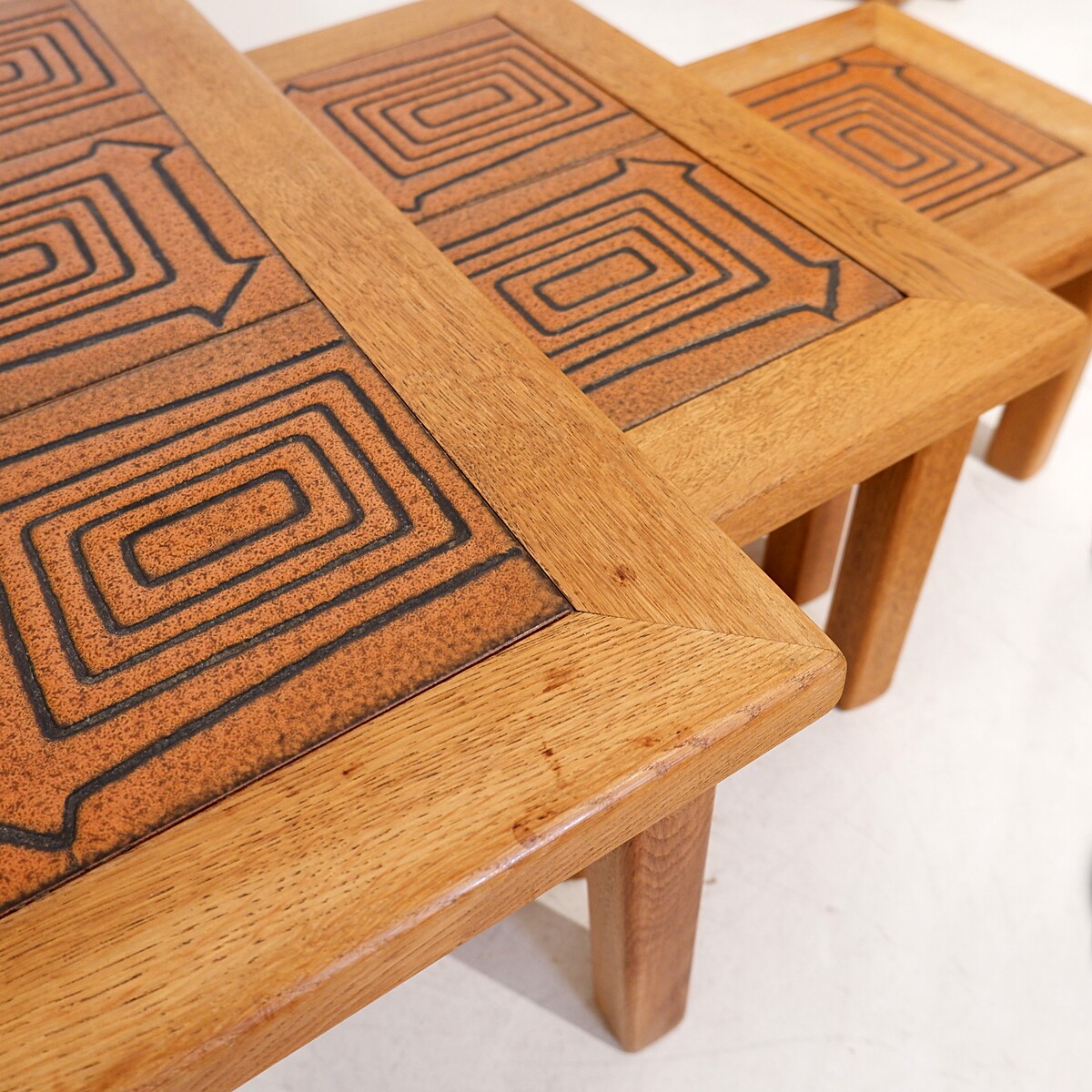 Brutalist solid oak nesting tables with geometric-patterned tiles
